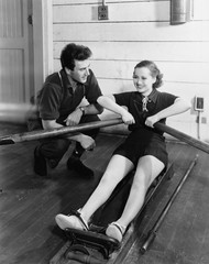 Man with woman using rowing machine 