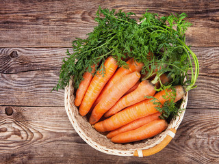 Ripe carrots in a basket on an old table