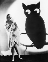 Young woman looking at a shadow of an owl with her finger on her lips 