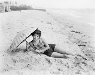 Woman lying at the beach with a sun umbrella 