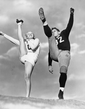 Cheerleader and football player kicking into the air 
