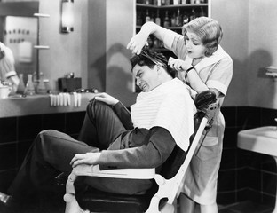 Woman barber cutting a man's hair 