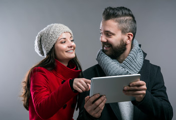 Young woman and man in winter coats with tablet