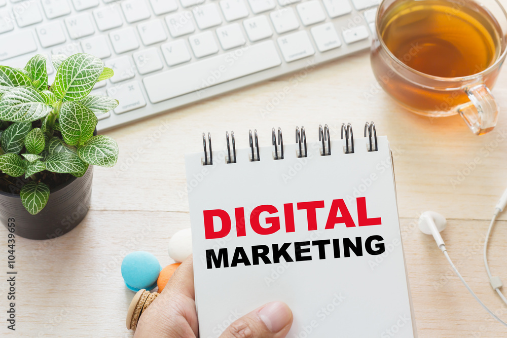 Aufkleber man holding digital marketing message on book and keyboard with a hot cup of tea, macaroon on the ta
