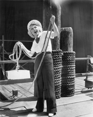 Fototapeta na wymiar Ahoy, from a young woman in a sailor's outfit, holding a heavy rope 