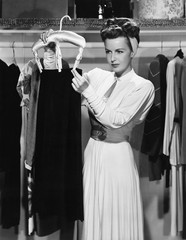 Young woman hanging up a skirt in the closet 