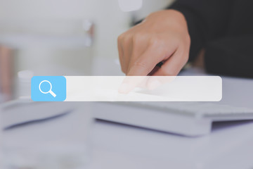 search bar on a virtual screen with his finger activating a global online computer search for a...