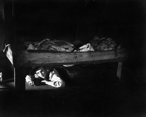 Young woman hiding under the bed 