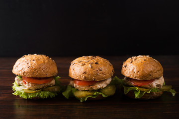 Three burgers on a dark wooden table