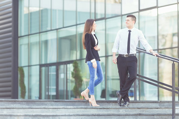 Two business people on a coffee break. Young businessman and businesswoman talking in front of the modern office building