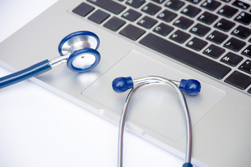 The blue stethoscope put on the laptop with white background