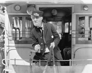 Conductor on a horse drawn streetcar holding the reins 