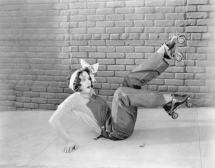 Young woman on the ground looking surprised after finding out that roller skating is a slippery...