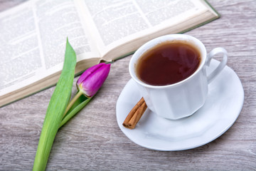 A cup of tea with cinnamon and purple tulip