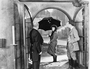 Young woman leaving a house with an umbrella to walk in the rain 