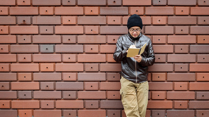Fototapeta na wymiar An Asian Man in a Brown Jacket with a Small Notebook