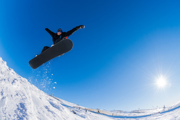 Snowboarder jumping against blue sky
