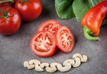 Sliced tomatoes, cashews and sweet chilli on textured background.