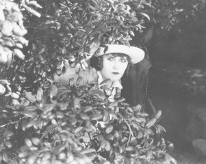 Woman peeking through bushes 