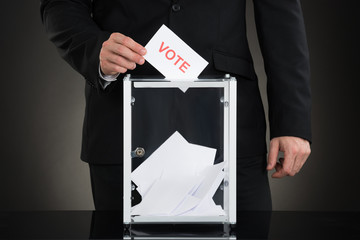 Male Hand Putting Vote Into A Ballot Box