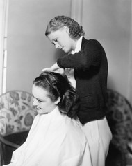 Obraz na płótnie Canvas One woman doing an other woman's hair 
