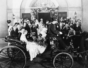 Fototapeta na wymiar Newlyweds leaving wedding in carriage 