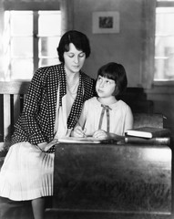 Girl sitting with her teacher in a class room 