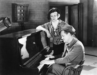 Man playing the piano while a woman is listening  - Powered by Adobe