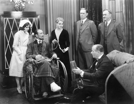 Man in a wheel chair with a broken foot and a group of people 