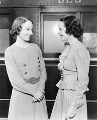 Two women standing in front of a train and smiling 