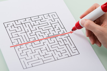 Woman Hand Drawing Straight Red Line Over Maze