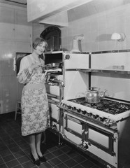 Woman with large stove holding pan 