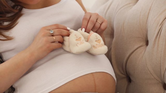 Pregnant woman belly holding baby booties. Healthy pregnancy.