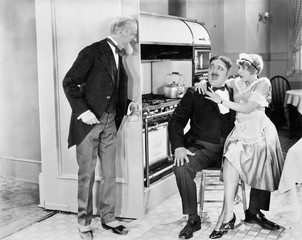 Young housekeeper sitting on the lap of her lover in the kitchen 