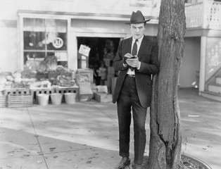 Detective leaning against tree taking notes 