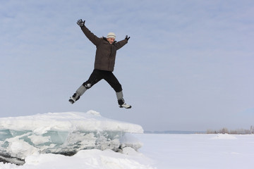 The man with a beard in a gray cap jumping from an block of ice in the snow
