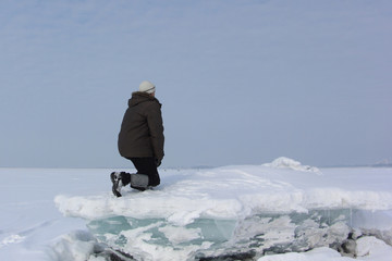 Fototapeta na wymiar The man in a gray cap sitting on an ice block looking afar