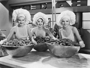 Three women with huge bowls of donuts 