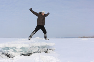 The man with a beard in a gray cap jumping from an block of ice in the snow
