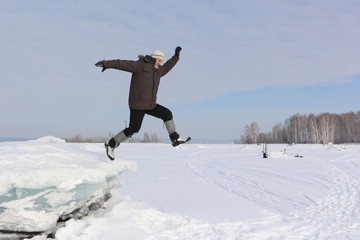 The man with a beard in a gray cap jumping from an block of ice in the snow
