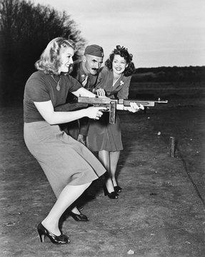 Two Young Women And A Soldier Trying Out A Machine Gun 