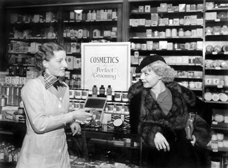 Two women in a drug store looking at each other  - 104453660