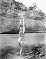 Woman hanging from rope swing over water 