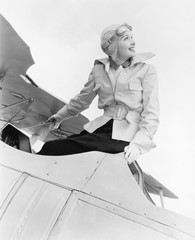 Young woman sitting on top of a biplane with gargles and hat 