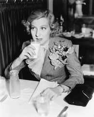 Young woman sitting at a table in a restaurant drinking milk 
