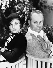 Couple sitting back to back together in a garden 