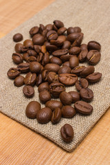 Heap of coffee beans on jute canvas on table