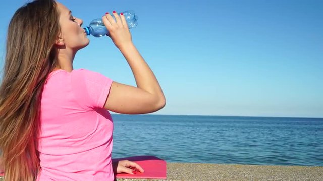 Woman resting after doing sports outdoors drinking water 4K