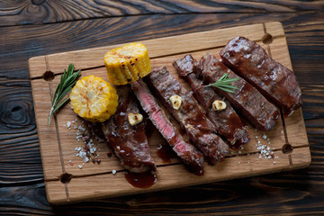 Sliced rancho beefsteak with sweetcorn on a wooden serving board