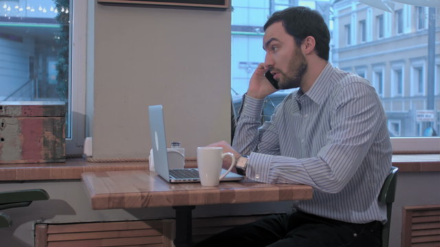 displeased businessman talking on the phone in cafe